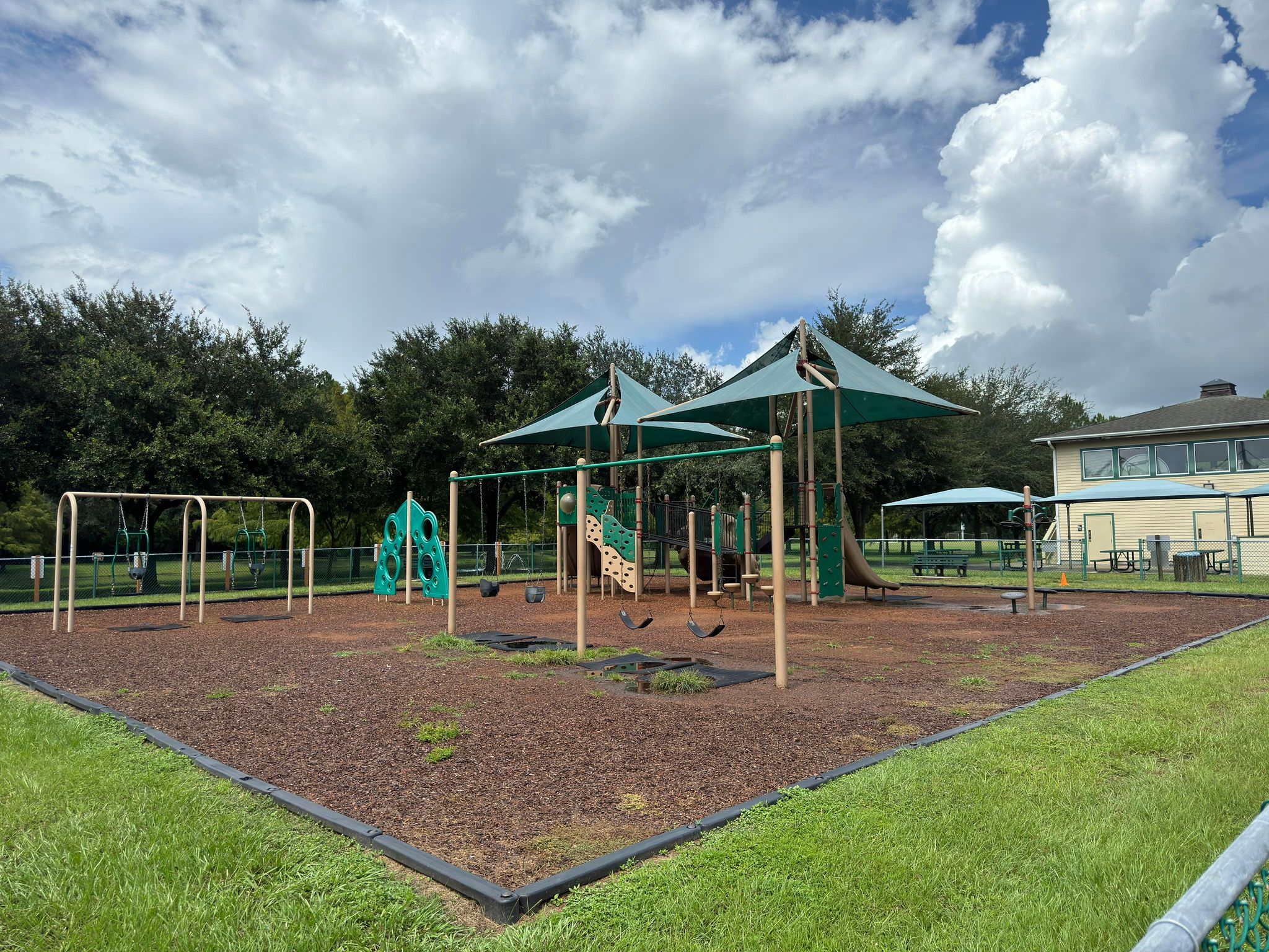 A playground with swing sets and big and small play structures for children.