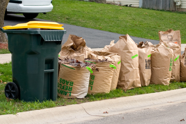 garbage can and bagged yard waste at the curb
