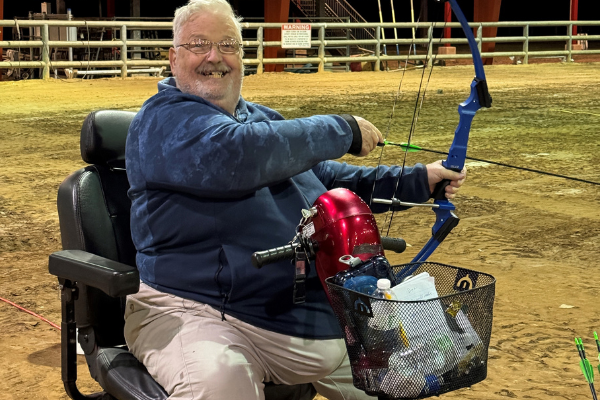 man in wheelchair smiling with bow
