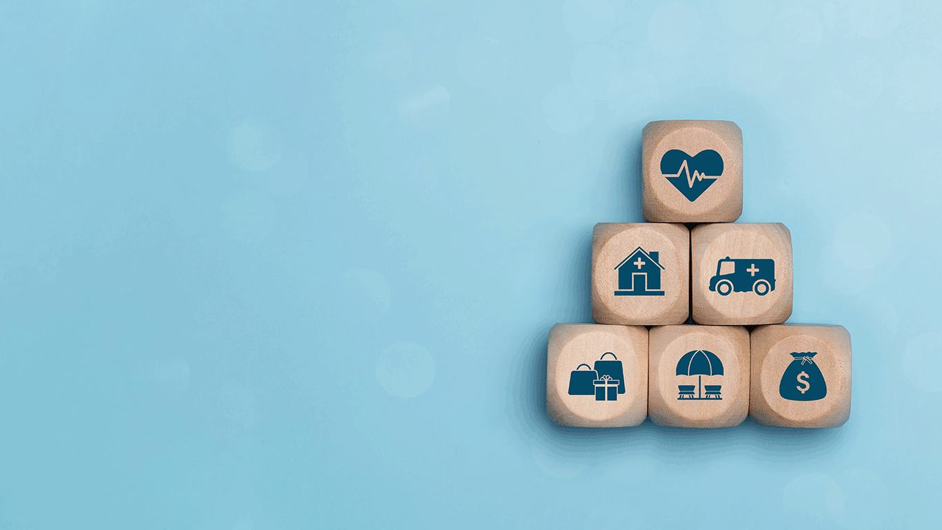 Building blocks with an icon of a heart, a house, an ambulance, shopping bags, a beach umbrella, and a bag of money, signifying all the blocks that make up a balanced lifestyle.