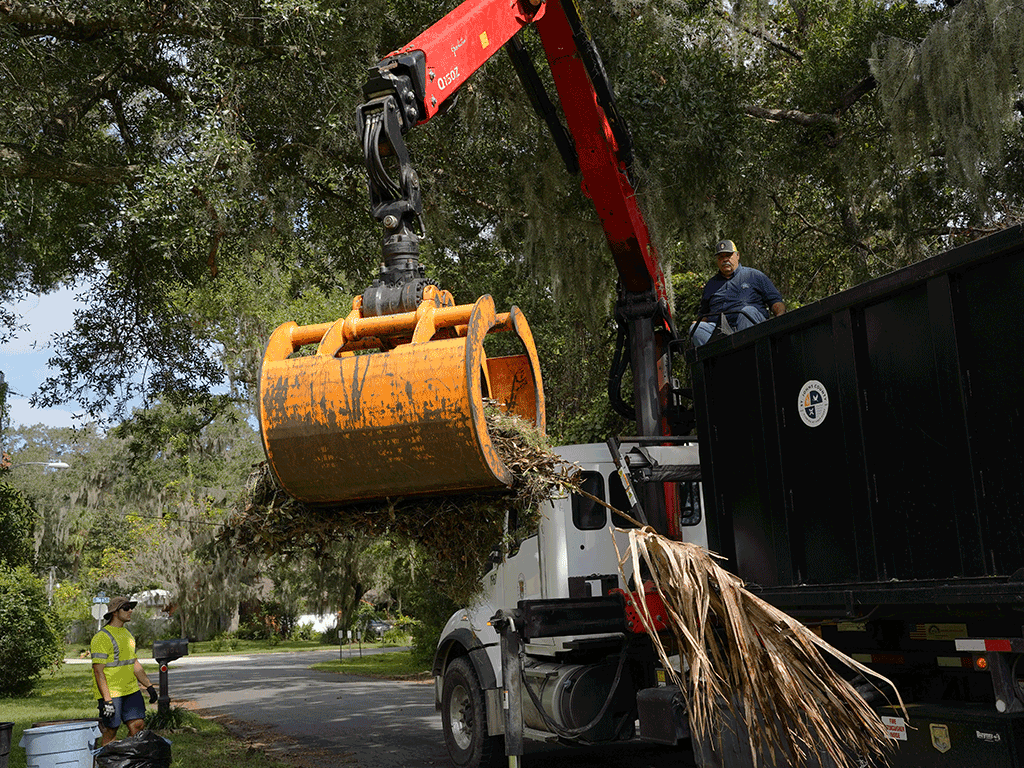 Workers clean up storm debris using a crane.