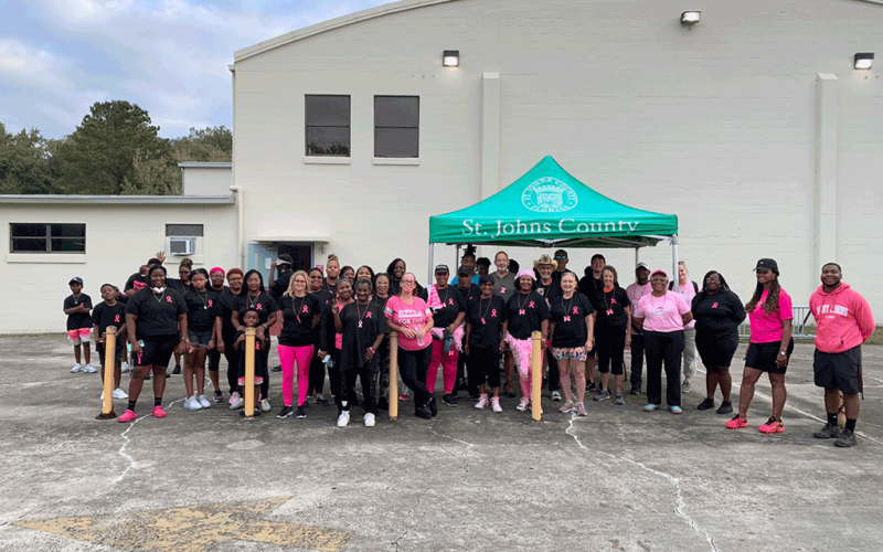 A large group of people in pink and black walking attire outside by a tent.