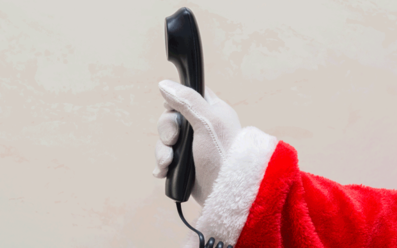 A gloved hand holds out a wired telephone.