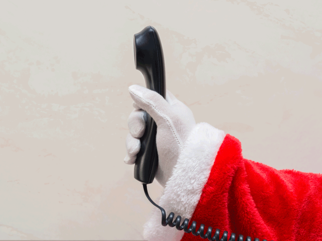 A gloved hand holds out a wired telephone.