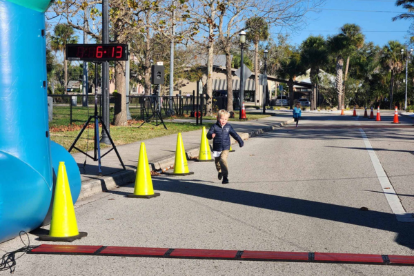 Two small children sprinting toward a finish line on a closed-off street.