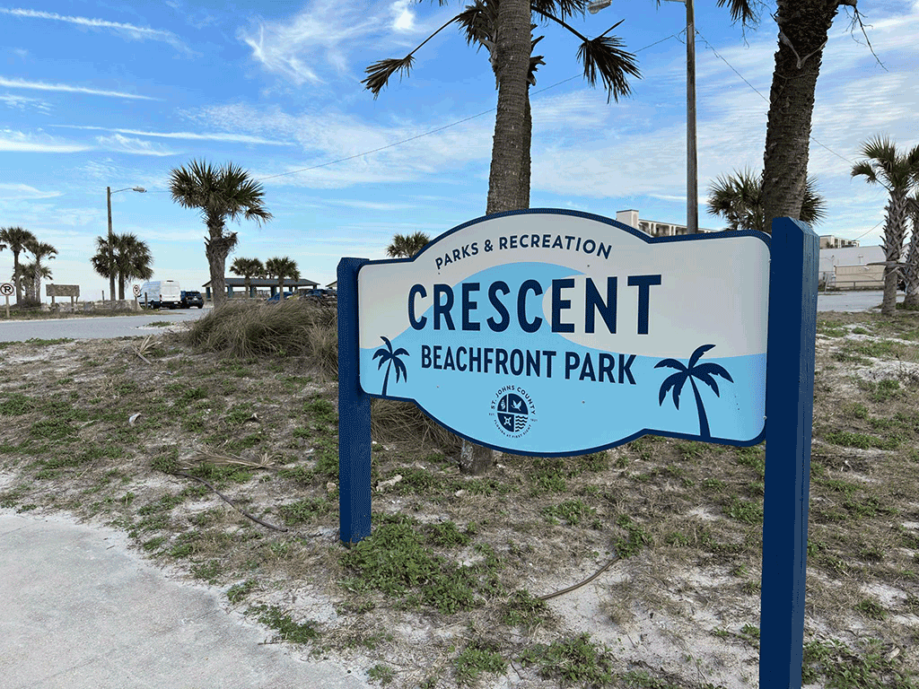 A sign at the entrance of a beach parking lot reads, ‘Crescent Beachfront Park.