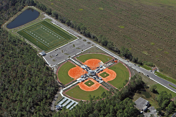 An overhead view of a park with baseball and softball fields, a multipurpose field, and a pond.