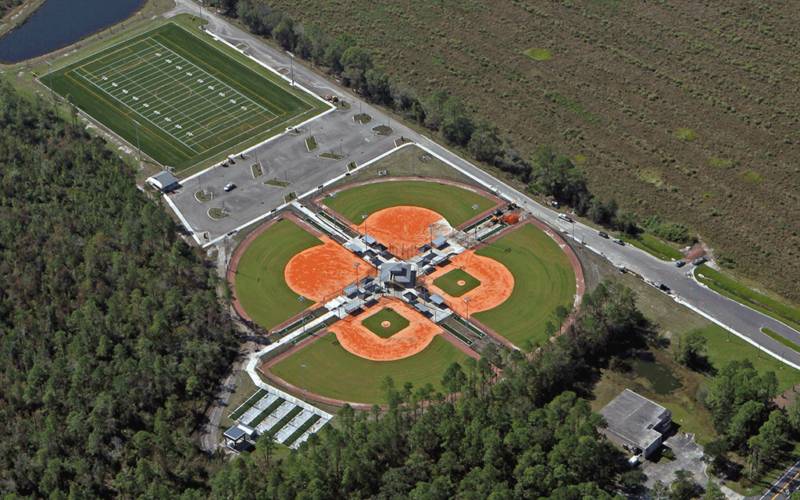 An overhead view of a park with baseball and softball fields, a multipurpose field, and a pond