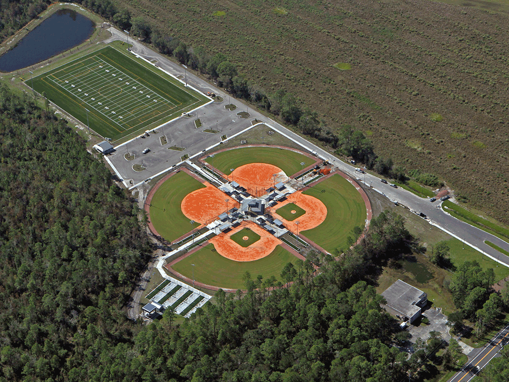 An overhead view of a park with baseball and softball fields, a multipurpose field, and a pond