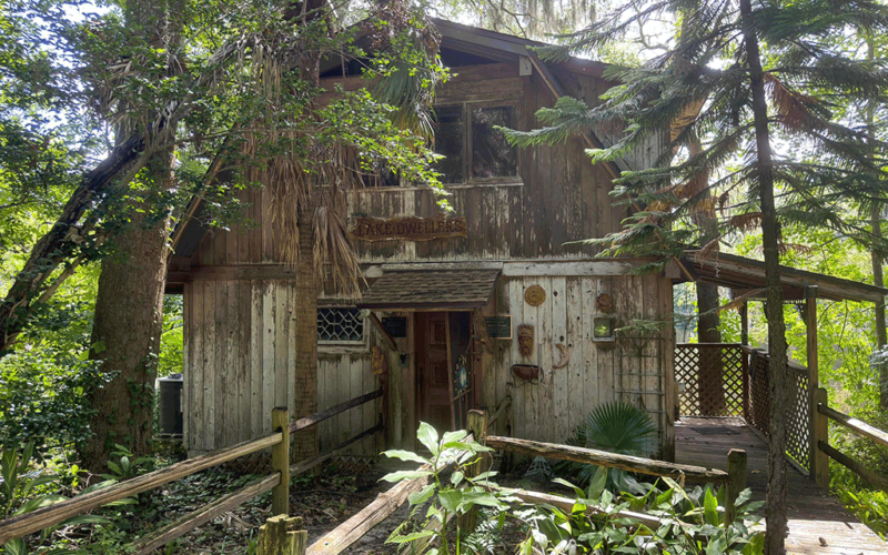 “An old wooden lake house surrounded by greenery