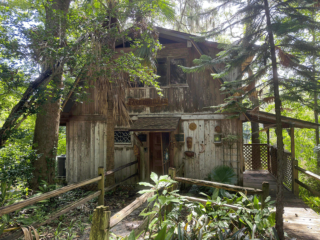 “An old wooden lake house surrounded by greenery